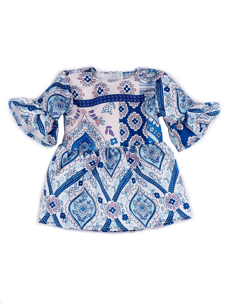 May include: A white and blue patterned dress with a ruffled sleeve. The dress has a paisley design with pink and blue accents.