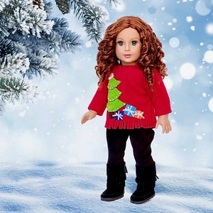 May include: A red doll sweater with a green Christmas tree and colorful presents. The doll is wearing black pants and brown boots.