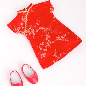 May include: A red dress with gold trim and a floral pattern, along with two red shoes.