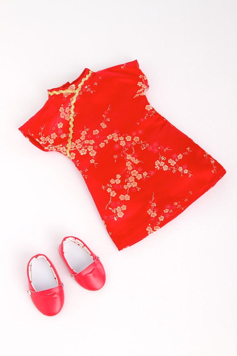 May include: A red dress with gold trim and a floral pattern, along with two red shoes.