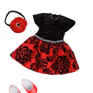 May include: A black and red dress with a short-sleeved black bodice, a red skirt featuring a black damask pattern, and a silver-toned beaded waistband. Included are a red fabric flower headband and a pair of solid red slip-on shoes.
