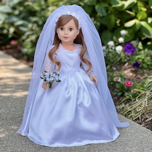 May include: A white satin wedding dress with lace sleeves and a long veil. The dress has a sweetheart neckline and a fitted bodice. The doll is holding a small bouquet of white flowers.