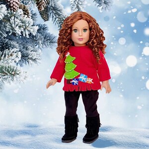 May include: A red Christmas sweater with a green felt Christmas tree and colorful felt presents. The sweater has a fringed hem and is worn by a doll with long, curly red hair.