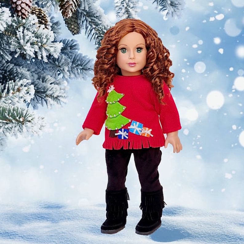 May include: A red Christmas sweater with a green felt Christmas tree and colorful felt presents. The sweater has a fringed hem and is worn by a doll with long, curly red hair.