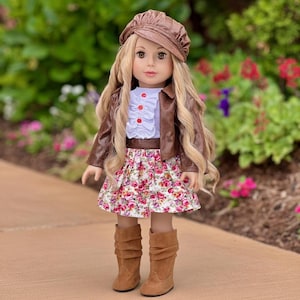 May include: A doll wearing a brown leather jacket, matching cap, and boots. The doll has long blonde hair and is wearing a white blouse with red buttons and a floral skirt with pink and red roses.