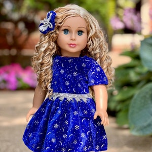 K&ouml;nnte beinhalten: Eine Puppe tr&auml;gt ein blaues Samtkleid mit silbernem Glitzer und einem Schneeflockenmuster. Das Kleid hat einen silbernen Besatz um die Taille. Die Puppe hat blonde lockige Haare und blaue Augen.