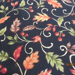 May include: Close-up of a fabric with a dark blue background. The fabric features a repeating pattern of autumn leaves in shades of orange, red, and green, along with small red berries and white swirling vines. The date 04/02/2018 is visible in the bottom right corner.