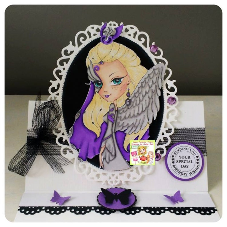 May include: A purple and grey angel with blonde hair and wings is featured on a white card with a black and white lace border. The card has a purple circle with the text "Sending You Your Special Day Birthday Wishes".