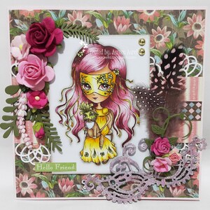 May include: A handmade card with a pink and yellow masked girl holding a small animal. The card has a floral background and a pink and white lace border. The text "Hello Friend" is written on the card.