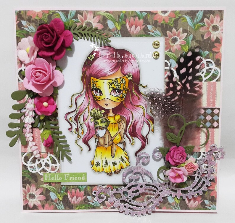 May include: A handmade card with a pink and yellow masked girl holding a small animal. The card has a floral background and a pink and white lace border. The text "Hello Friend" is written on the card.