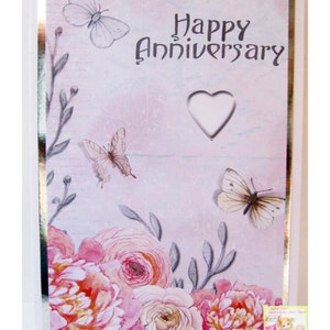 May include: A pink and white floral card with the text "On your Special Day" and "Happy Anniversary". The card features a heart-shaped cutout and butterflies.