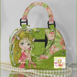 May include: A green glitter handbag with a floral design and a fairy figurine inside. The handbag has a black handle and a black flap with a buckle. The fairy is wearing a pink dress and has green hair and wings. The text "New Release Team Stamps by Julia Spirit Anna" is visible in the lower right corner.