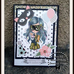 May include: A handmade card with a black and white polka dot background. The card features a girl with blue hair wearing a mask and holding a small animal. The card also has a pink flower, a party hat, and balloons. The text "Be-you-tiful" is on the card. The card is signed "Ewa DT World Wide Design Team".