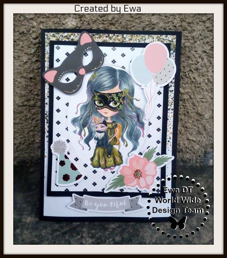May include: A handmade card with a black and white polka dot background. The card features a girl with blue hair wearing a mask and holding a small animal. The card also has a pink flower, a party hat, and balloons. The text "Be-you-tiful" is on the card. The card is signed "Ewa DT World Wide Design Team".