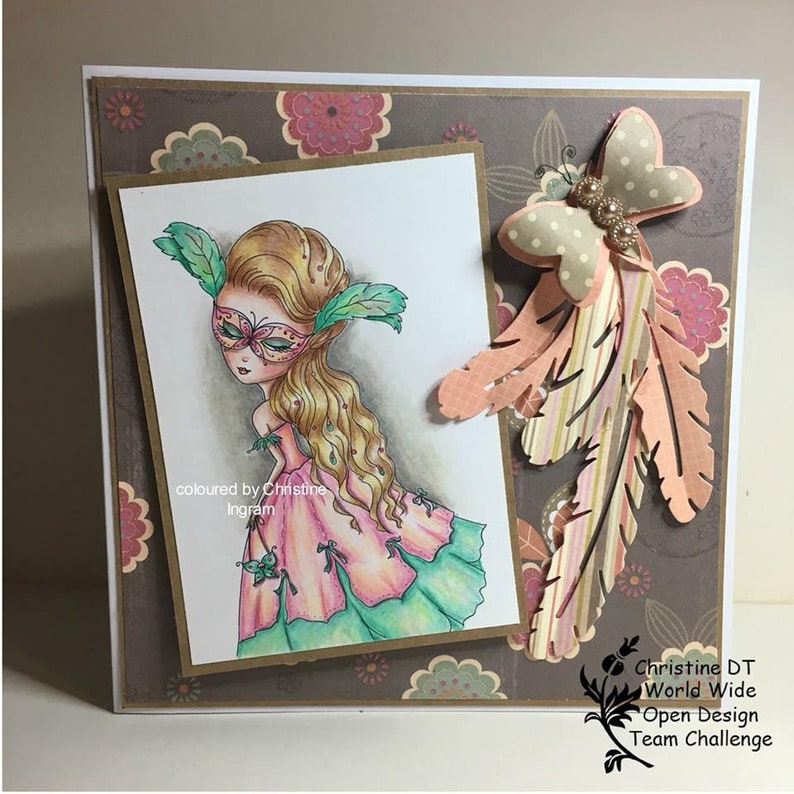 May include: A card with a hand-drawn illustration of a girl wearing a masquerade mask and a pink dress. The card is decorated with a butterfly and feathers. The text "coloured by Christine Ingram" is written on the card.