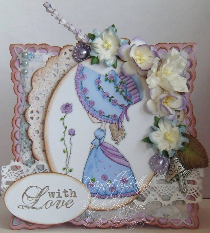 May include: A handmade card with a pink background and a white oval in the center. The oval features a drawing of a girl in a blue dress and a hat, with flowers and vines around her. The card also has a white oval at the bottom with the words "with love" written in cursive.