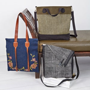 May include: Three fabric bags in different styles. A denim tote bag with floral embroidery and leather straps. A green and brown shoulder bag with a top handle. A black and white messenger bag with a flap.