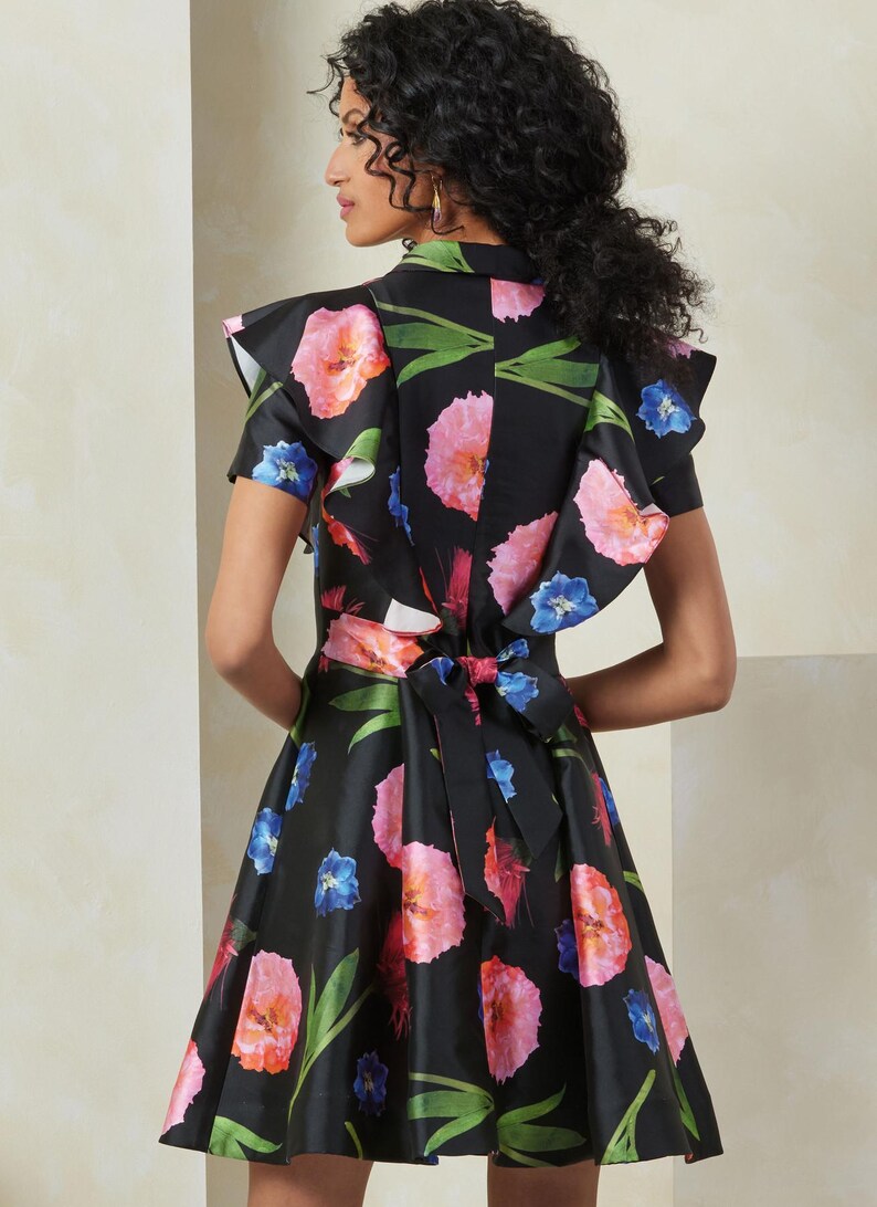 Puede incluir: Un vestido negro con estampado floral con flores rosas, azules y verdes. El vestido tiene un cuello y mangas con volantes, y un lazo en la espalda.
