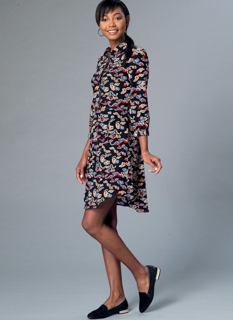 May include: A black dress with a cloud pattern in red, white, and blue. The dress has a collared neckline, long sleeves, and a slightly flared skirt. The model is wearing black loafers.