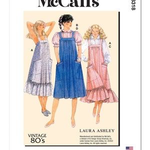 May include: A vintage McCall's sewing pattern for a Laura Ashley dress. The pattern shows three women wearing different versions of the dress: one in blue denim, one in pink floral print, and one in white floral print. The pattern is from the 1980s and is designed and printed in the USA.