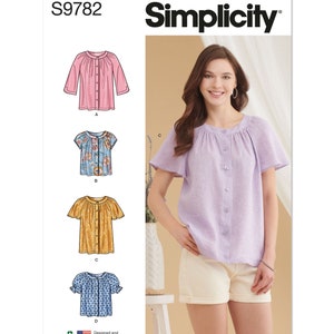 May include: Simplicity sewing pattern S9782. The image shows a woman wearing a light purple button-down blouse with short sleeves. The pattern includes illustrations of various blouse styles, including a pink long-sleeve blouse and a blue floral top.