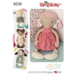 May include: A sewing pattern for making three different dolls. The dolls are all wearing dresses and have pigtails. The pattern is from Simplicity and is for Whimsy Dolls. The pattern number is 8539.