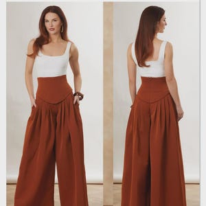 May include: Vogue Patterns sewing pattern featuring a two-piece outfit. The outfit includes a white square-neck tank top and high-waisted, wide-leg rust-colored pants. The pattern is designed and printed in the USA.