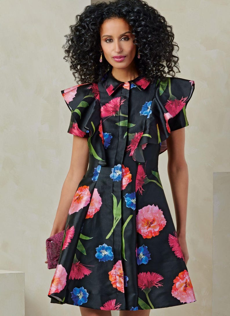 Puede incluir: Un vestido negro de estampado floral con cuello de volantes y mangas cortas. El vestido tiene un cierre de botones en la parte delantera y una falda acampanada.