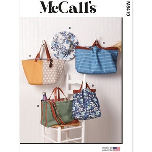 May include: McCall's M8419 sewing pattern for four different tote bags. The bags are made of various fabrics, including striped, polka dot, floral, and solid colors. The bags are hanging on hooks and a chair.