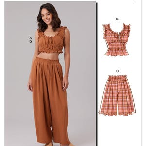 May include: McCall's sewing pattern M8634 featuring a two-piece outfit. The outfit includes a crop top and wide-leg pants in a rust-colored fabric. The top has ruffled edges and a tie detail. The pattern is designed and printed in the USA.