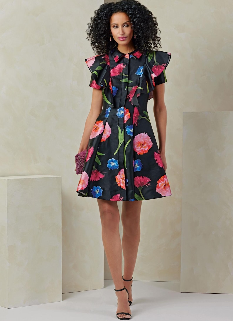 Puede incluir: Un vestido negro de estampado floral con cuello de volantes y mangas cortas. El vestido tiene un cierre de botones en la parte delantera y una falda acampanada.