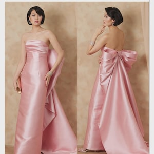 May include: A strapless, floor-length pink satin gown with a large bow detail on the back. The image shows the front and back views of the dress. The Vogue Patterns logo and the text "V2177" are visible.