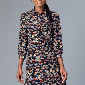 May include: Black dress with a colorful cloud pattern. The dress has a collared neckline, long sleeves, and a button-down front. The dress is knee-length and has a fitted waist. The cloud pattern includes orange, yellow, and blue accents.