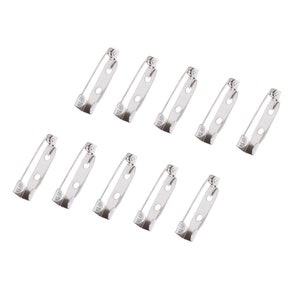 May include: Ten silver-toned safety pin closures. The pins are approximately 1 inch long and have a pointed end and a loop for attaching to fabric.