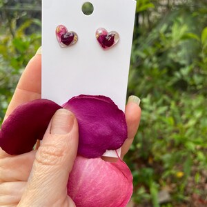 May include: A pair of heart-shaped earrings with real pressed rose petals and gold flakes encased in clear resin.