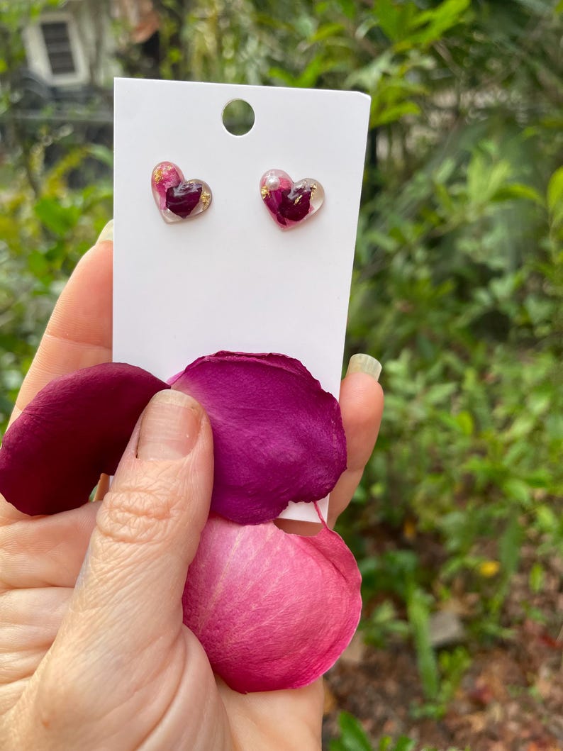 May include: A pair of heart-shaped earrings with real pressed rose petals and gold flakes encased in clear resin.