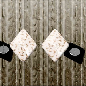 Puede incluir: Dos posavasos blancos con un patrón dorado y dos posavasos negros con un círculo de metal plateado en el centro.