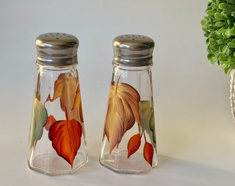 Painted salt and pepper shakers fall leaves. They are 3oz volume, tapered with stainless steel tops, earth tone colors for any table.