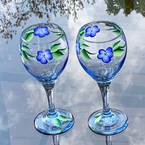 Painted wine glasses with blue flowers all around on a soft blue colored glass. Listing is for set of 2.