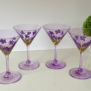 May include: Four purple glass martini glasses with hand-painted purple flowers and gold accents.