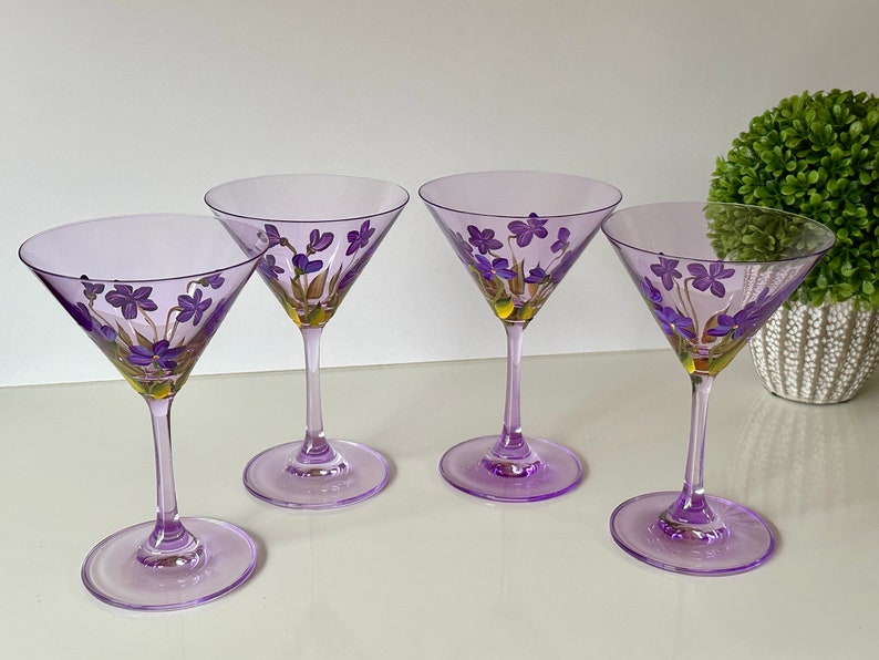 May include: Four purple glass martini glasses with hand-painted purple flowers and gold accents.
