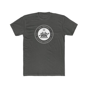 Peut inclure: Un t-shirt gris foncé avec un logo circulaire blanc qui dit "Rio Grande Rafting Company" et qui représente un radeau avec des personnes à bord. Le logo indique également "Est. 1912".