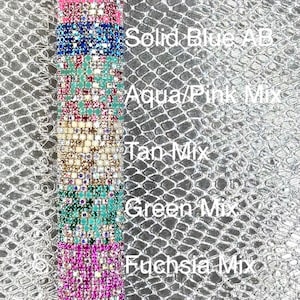 May include: A vertical display of various rhinestone colors, including coral, solid blue, aqua/pink, tan, green, fuchsia, and blue. Each color is labeled with its name. The background is a textured silver surface.