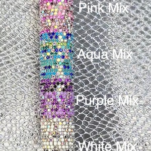 May include: A decorative pen with sections of pink, aqua, purple, and white crystal embellishments. The pen has the words "Pink Mix", "Aqua Mix", "Purple Mix", and "White Mix" written vertically on the side.