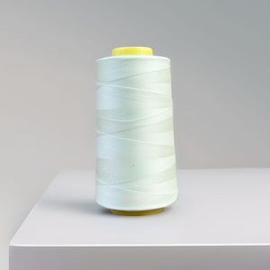 May include: A spool of light green thread with a yellow plastic top.