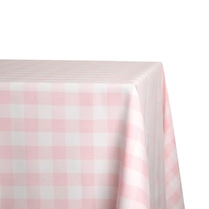 May include: A pink and white checkered tablecloth. The fabric is folded over a surface, showcasing the pattern. The tablecloth has a classic gingham design, with a soft, pastel color palette.