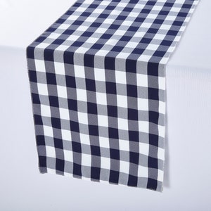May include: A white and navy blue checkered table runner. The runner is made of a soft, woven fabric and has a subtle sheen.