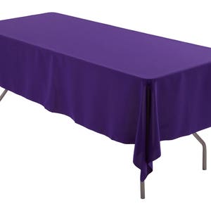 May include: A purple rectangular tablecloth draped over a table with silver legs.