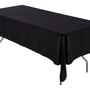 May include: A black rectangular tablecloth draped over a table with silver legs. The tablecloth has a smooth, silky texture and hangs down on all sides.