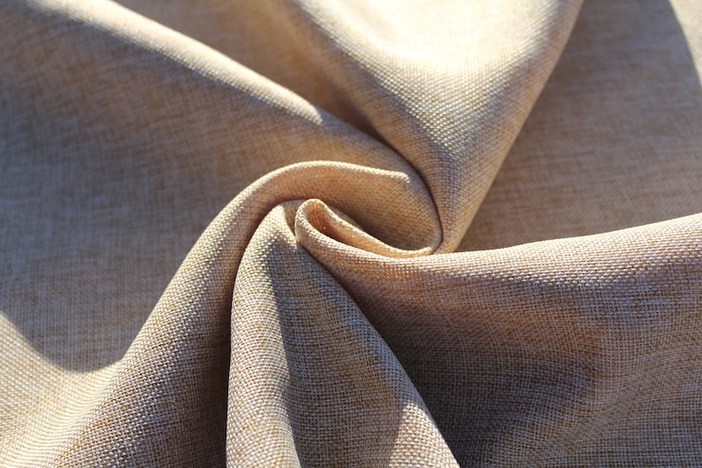May include: Close-up of a beige fabric with a textured weave. The fabric is folded and twisted, creating a swirling pattern.